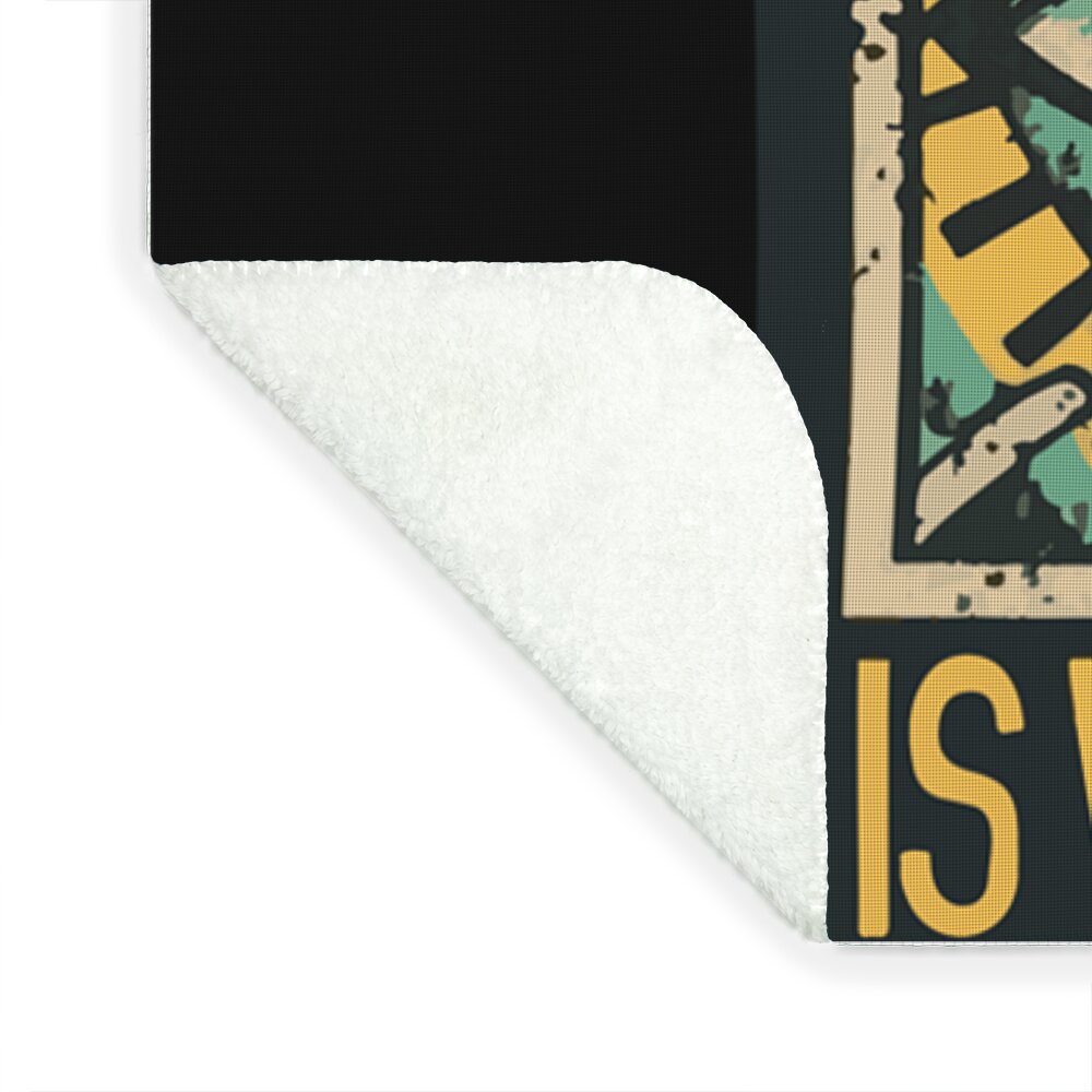 Black printed blanket corner with white plush underside and partial eye-text graphic