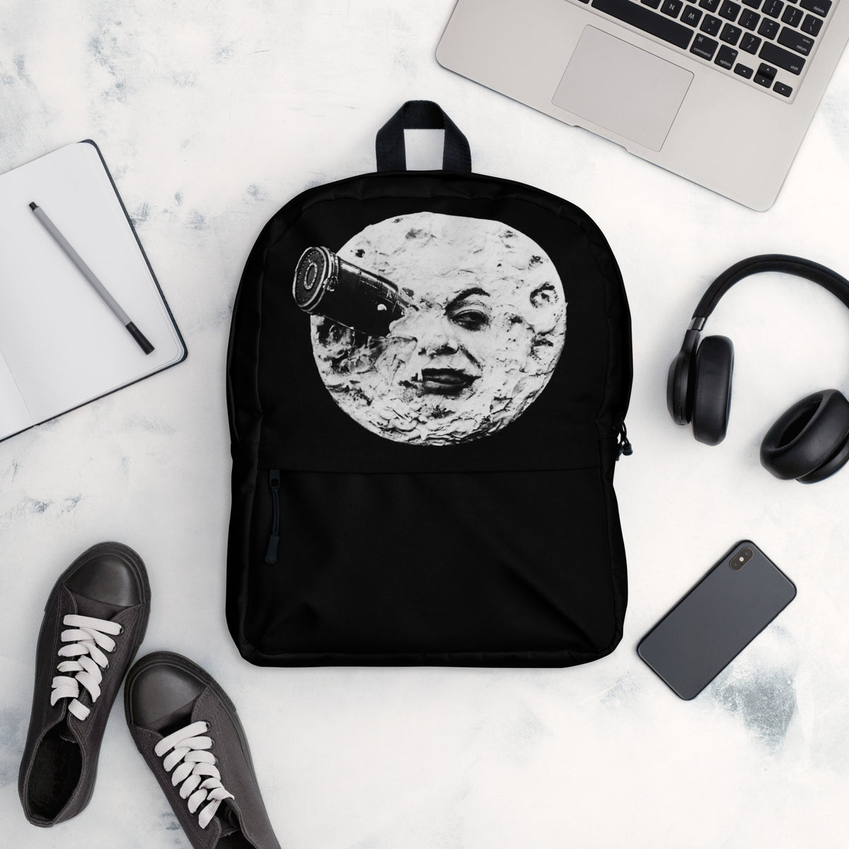 Black backpack with moon face graphic, front view laid flat