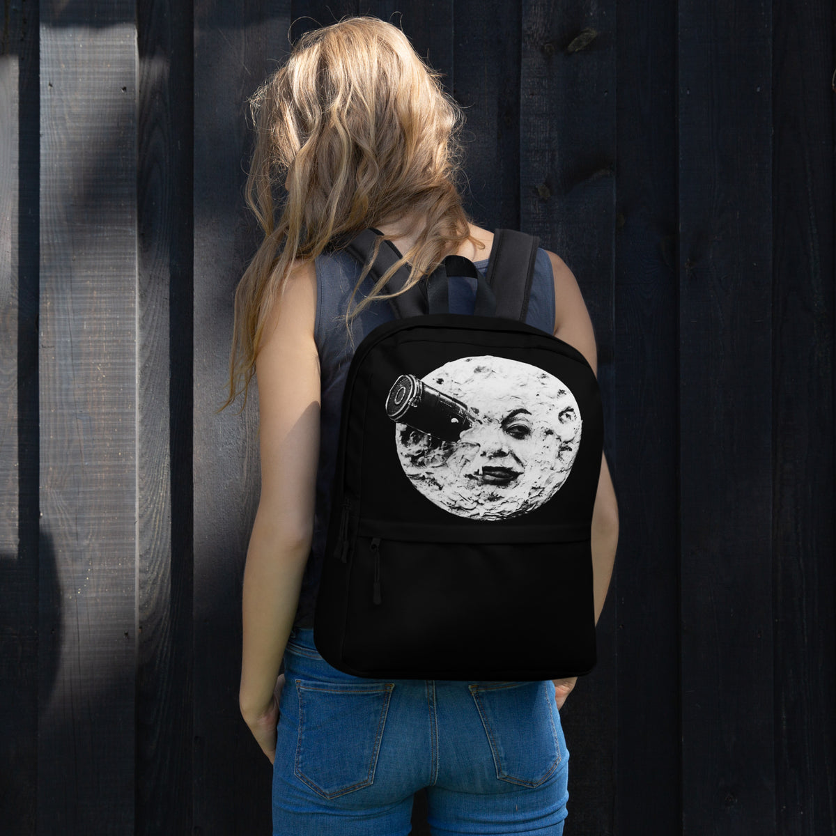 Black backpack with moon face graphic, worn on back with front top pocket