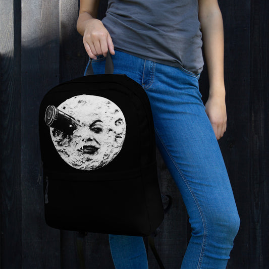 Black backpack with round moon face graphic and top handle, held by one person