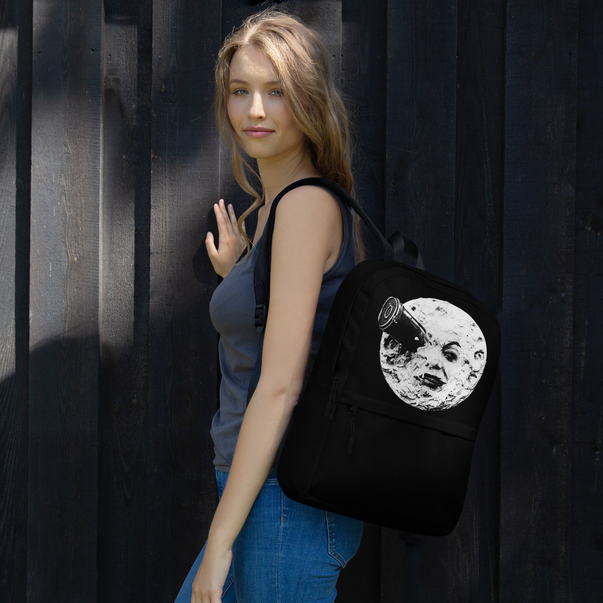 Black backpack with moon face graphic, worn on back with shoulder straps