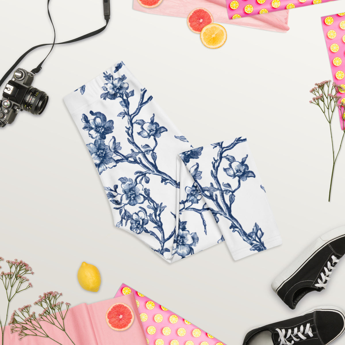 Folded white capri leggings with blue floral vine print, mid-calf length.