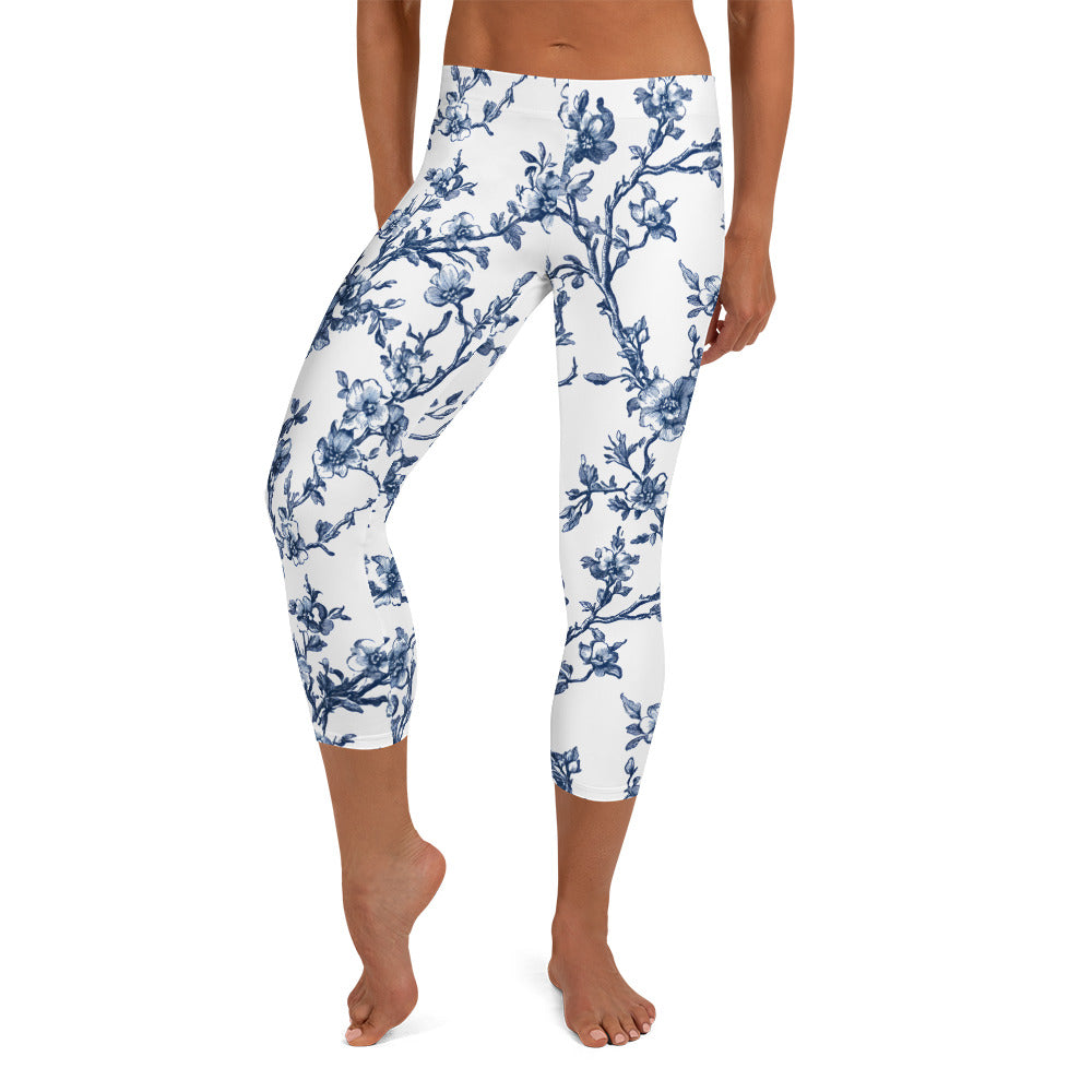 White capri leggings with blue floral print, tapered legs, mid-calf crop.