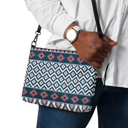 Aztec-pattern crossbody bag on person’s shoulder strap with blue, red, and white design