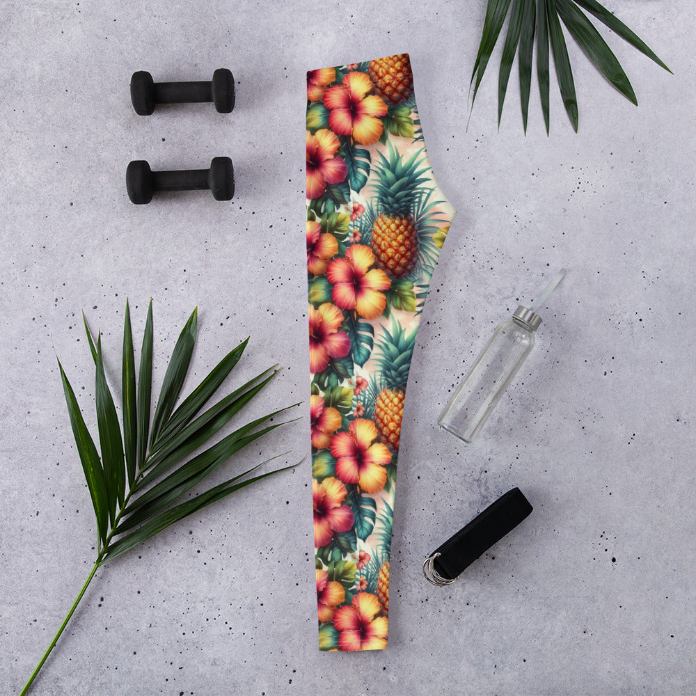 Tropical print leggings laid flat, hibiscus and pineapple flowers on green background