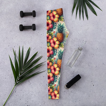 Tropical print leggings laid flat, hibiscus and pineapple flowers on green background
