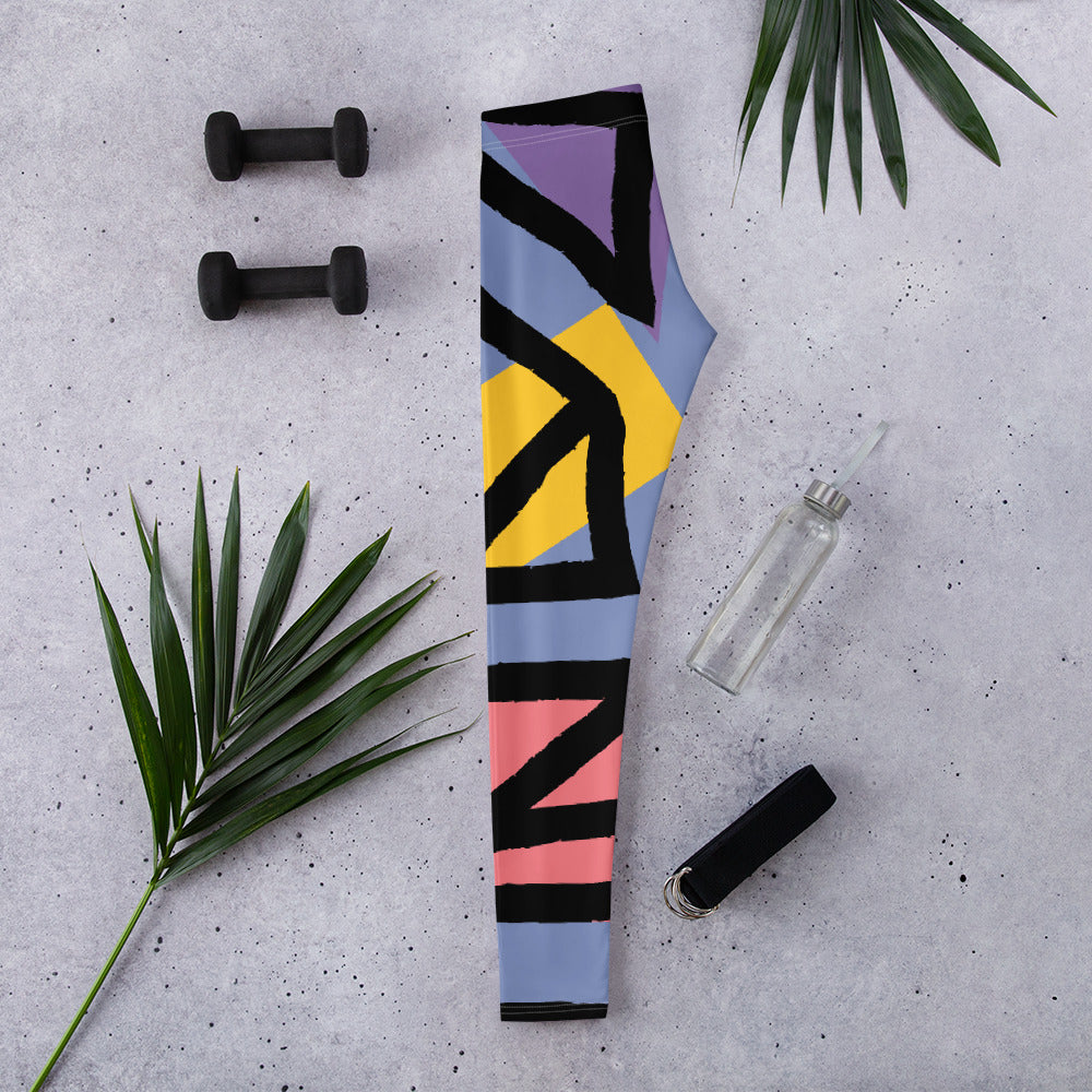 Folded blue geometric leggings with black, yellow, purple, and pink stripe shapes.