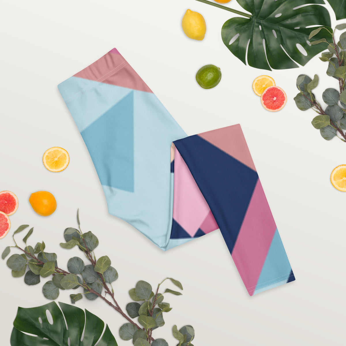 Two folded women’s leggings with pastel geometric print blocks and stripes, full length.
