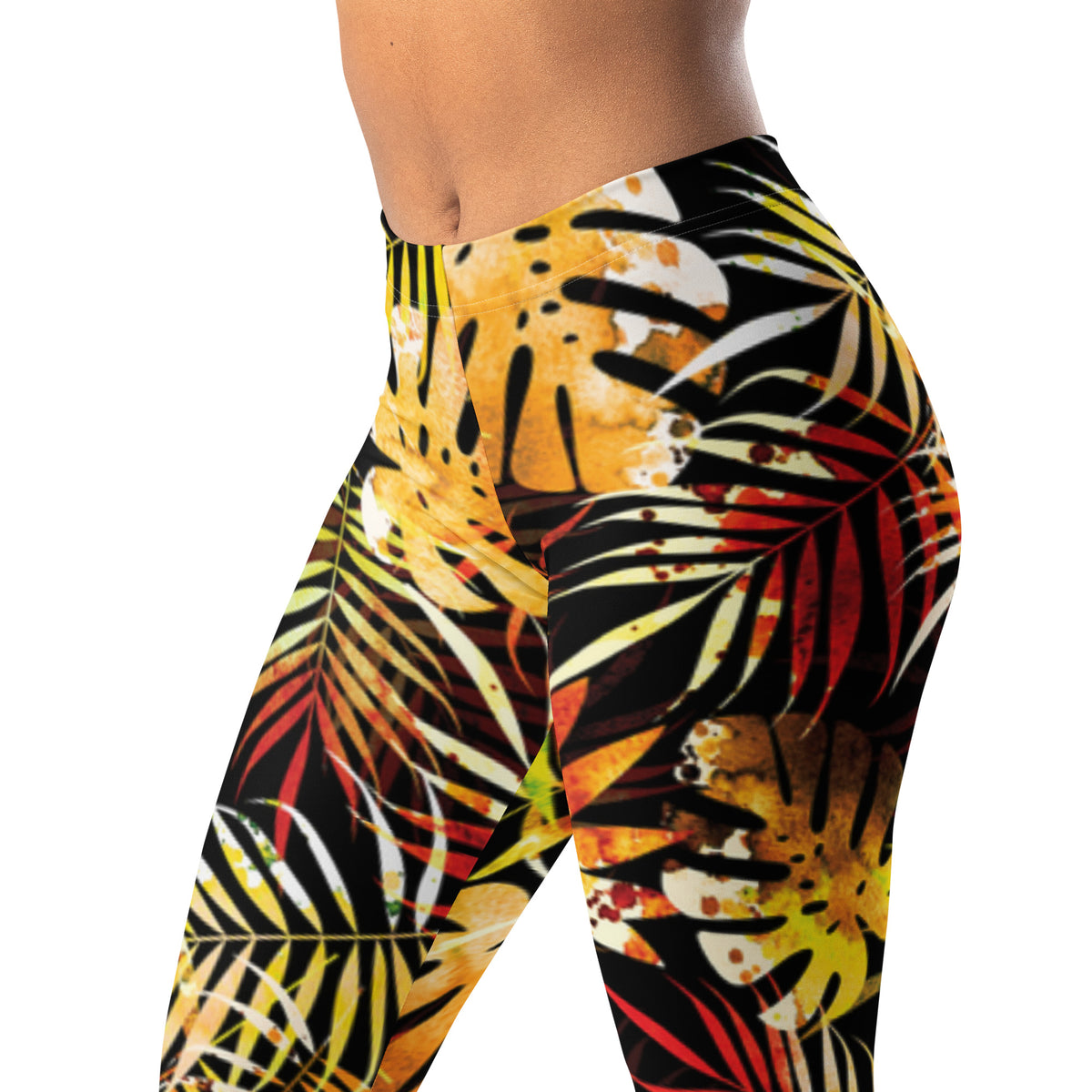 Women's leggings close-up with bold tropical leaf print in yellow and red on black