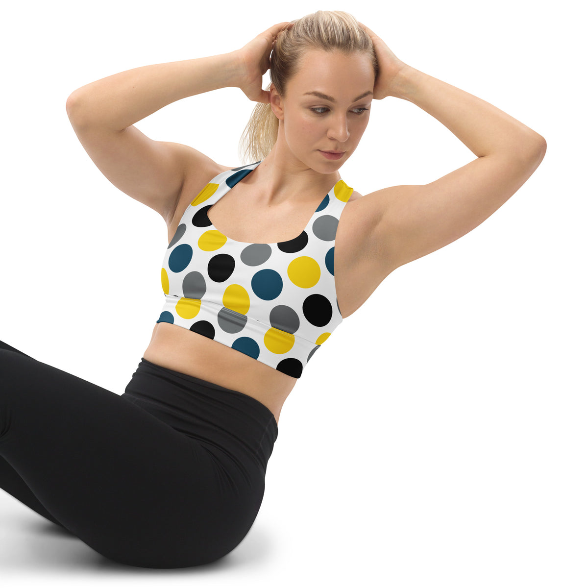 Longline sports bra with multicolor polka dots on a white base, sporty scoop neckline.