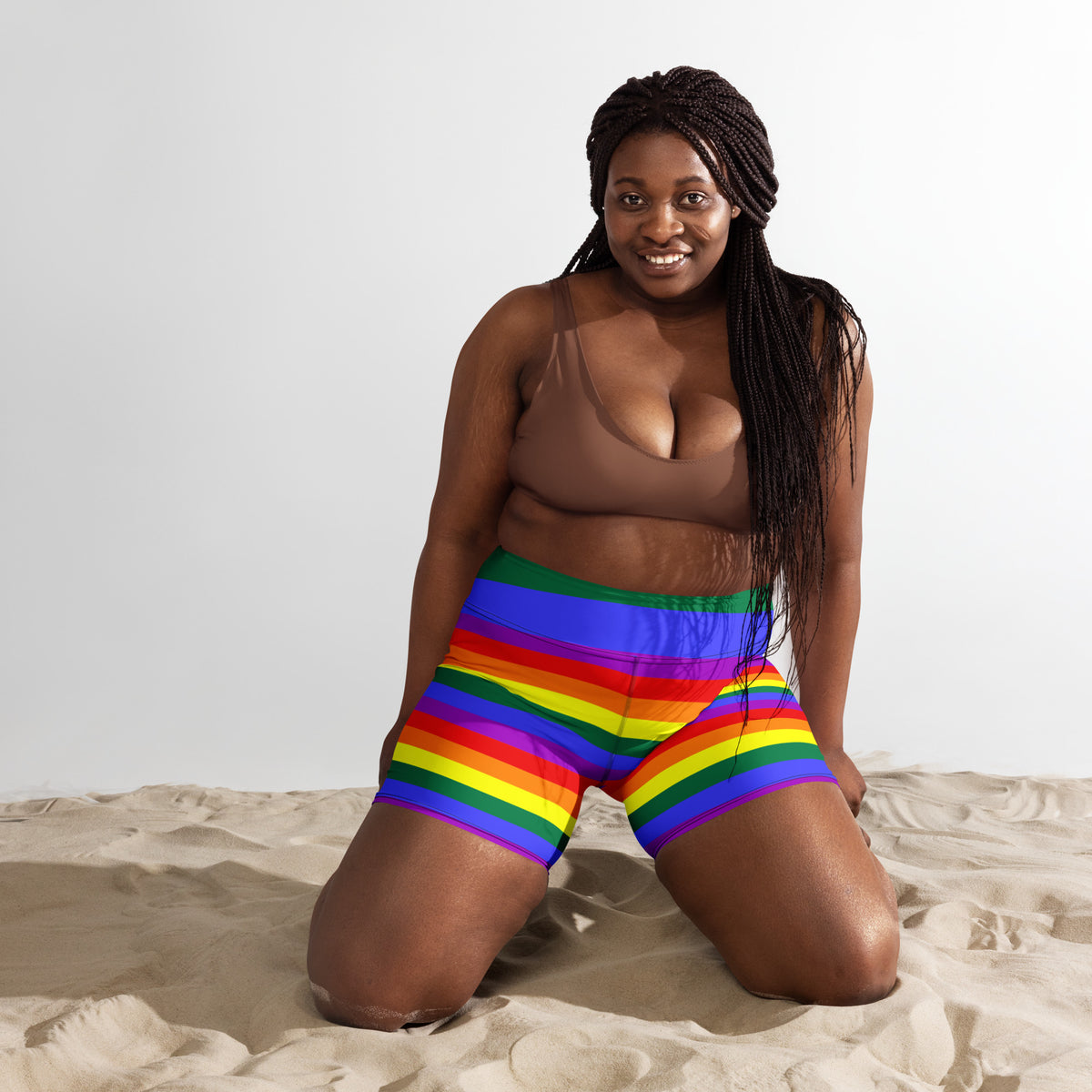 Rainbow striped yoga shorts with wide green waistband, model kneeling