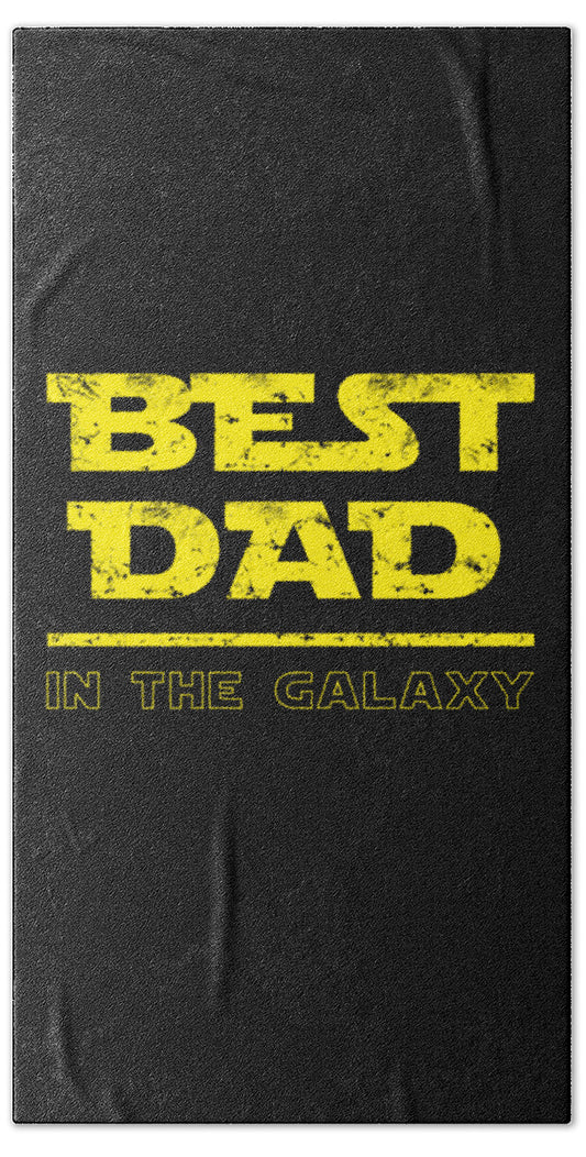 Black beach towel with yellow “Best Dad” and “In the Galaxy” text.