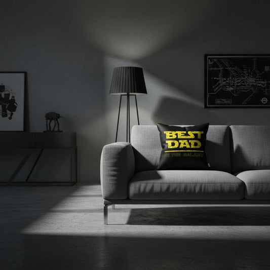 Throw pillow on gray sofa, black cover with yellow 'BEST DAD IN THE GALAXY' print