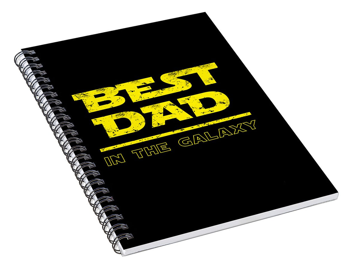 Spiral notebook, black cover with yellow 'BEST DAD IN THE GALAXY' text, angled view