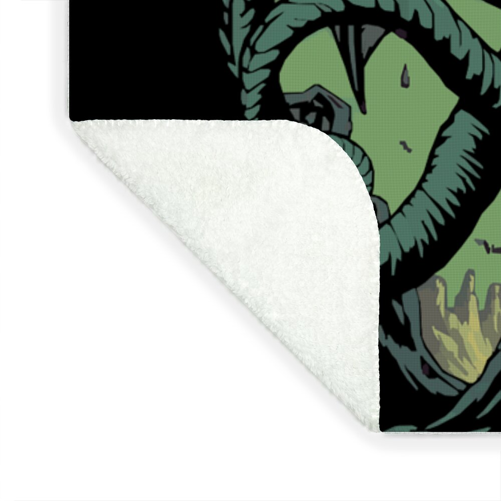 Throw blanket corner showing off-white plush backing and partial green demon print