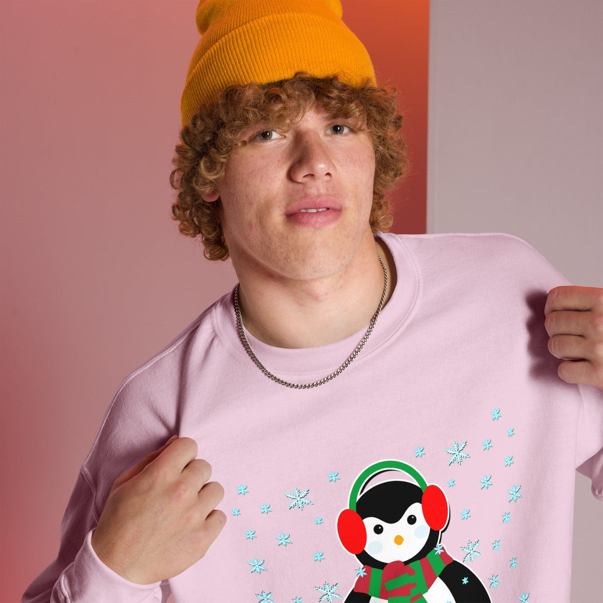 Light pink sweatshirt with long sleeves and a colorful penguin graphic with blue snowflakes.