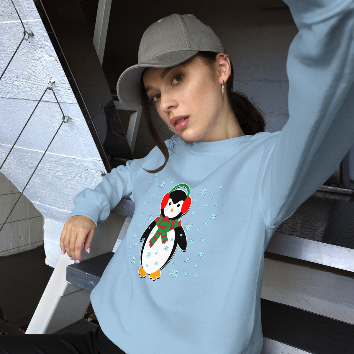Light blue sweatshirt with long sleeves and a colorful penguin graphic with snowflake details.
