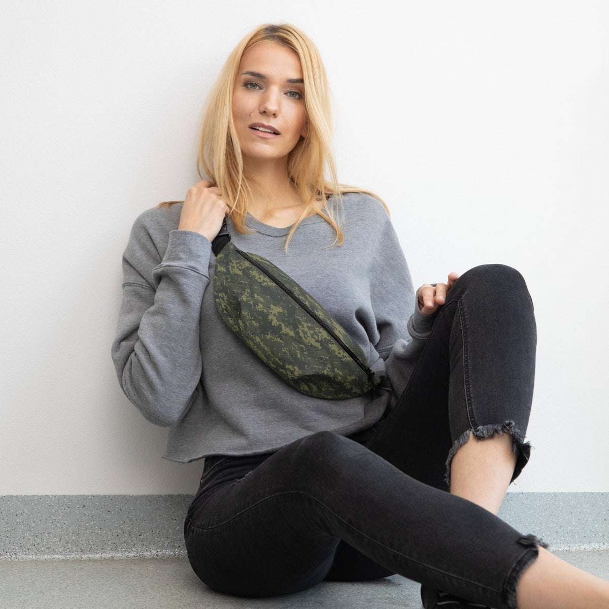 Camouflage waist bag worn across torso with black strap on dark pants