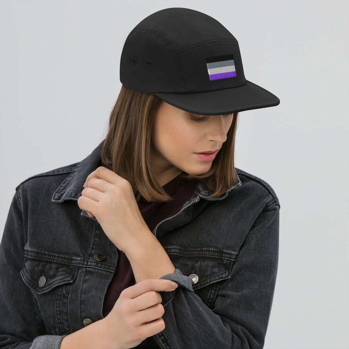 Black five-panel cap worn by a person, with embroidered purple-and-gray flag patch