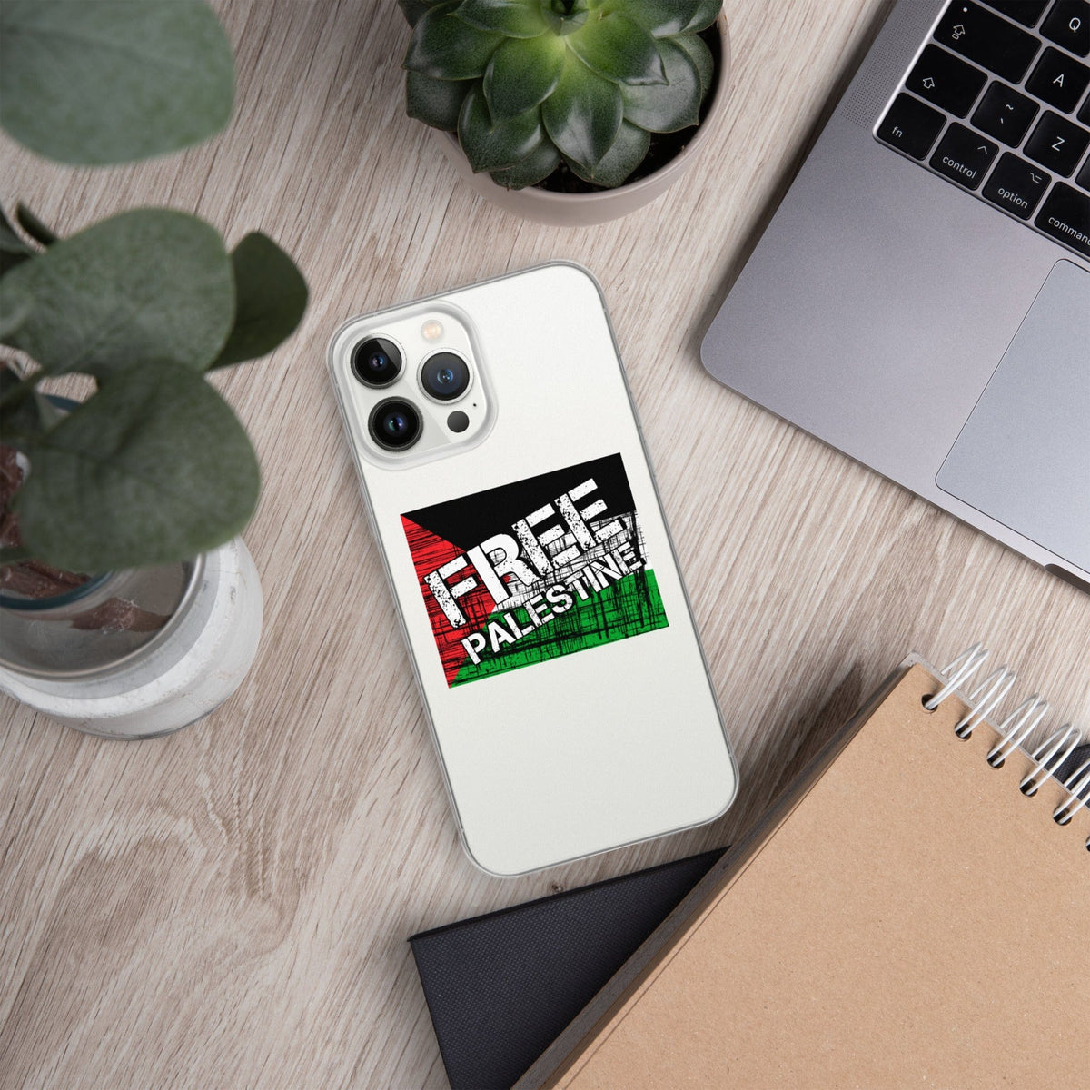 Clear iPhone case on desk surface with 'FREE PALESTINE' front graphic