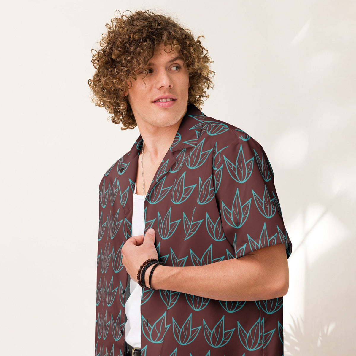 Unisex short-sleeve button shirt with teal leaf print and dark maroon fabric.