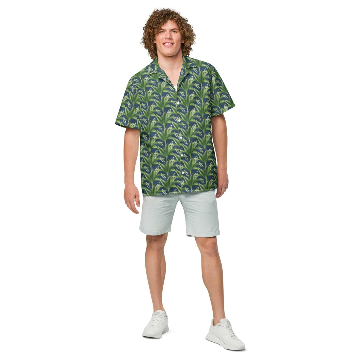Short-sleeve button-up shirt with blue-green leafy print, worn with light shorts.