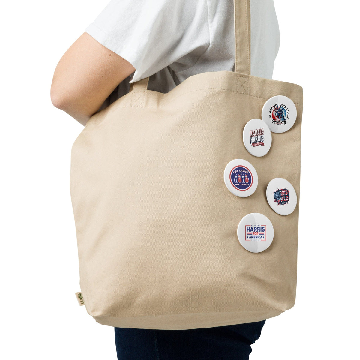 Five round pin buttons attached to a beige tote bag with front badge designs