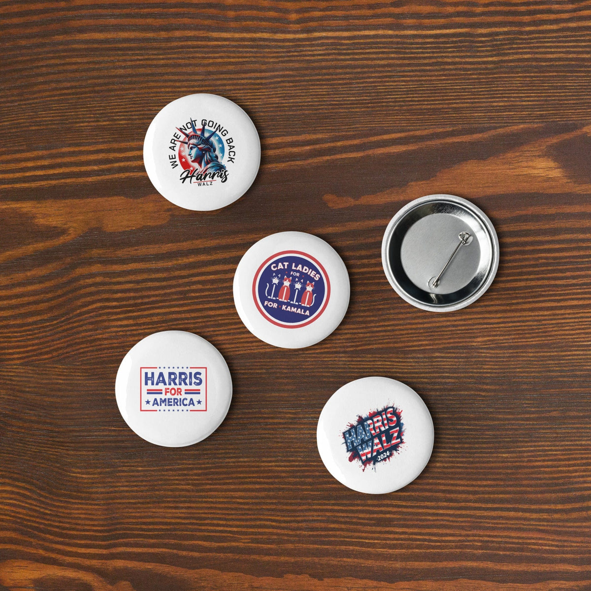 Five round pin buttons on a wooden surface with campaign text and cat-themed artwork