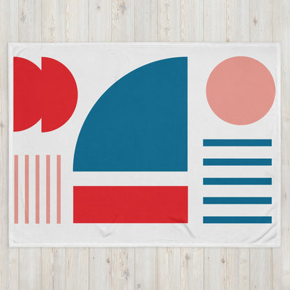 White throw blanket with big blue square, red shapes, pink circle, and stacked blue stripes.