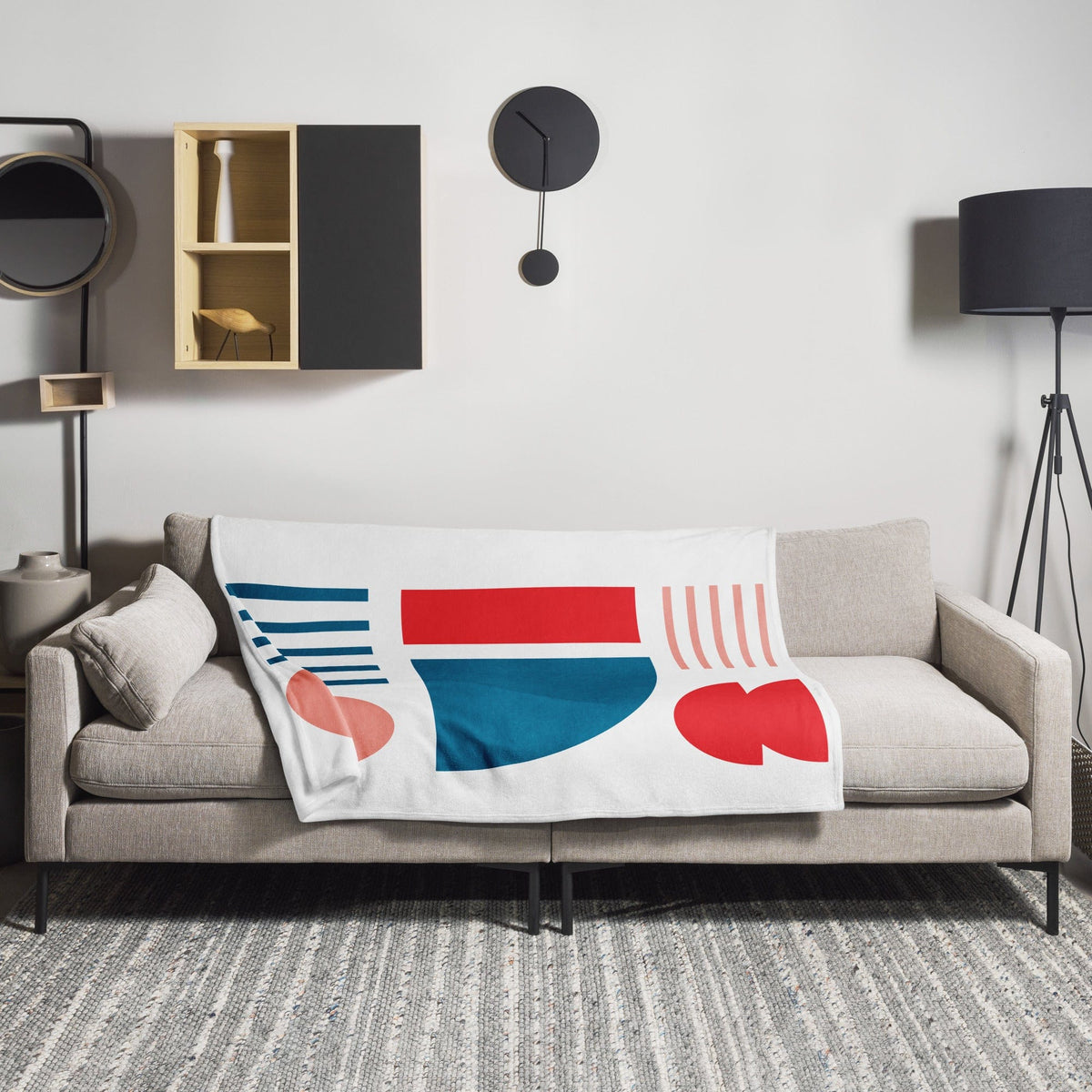 White throw blanket with teal, red, and blue abstract blocks and striped lines on sofa.