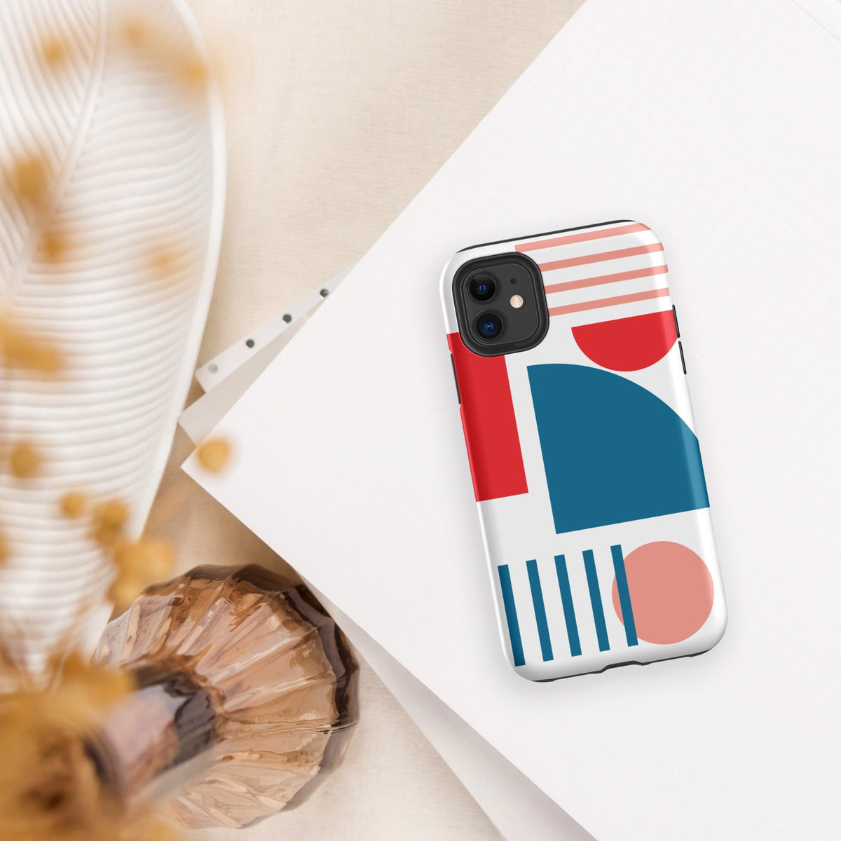 Tough iPhone case with red, blue, and coral geometric pattern on a white shell