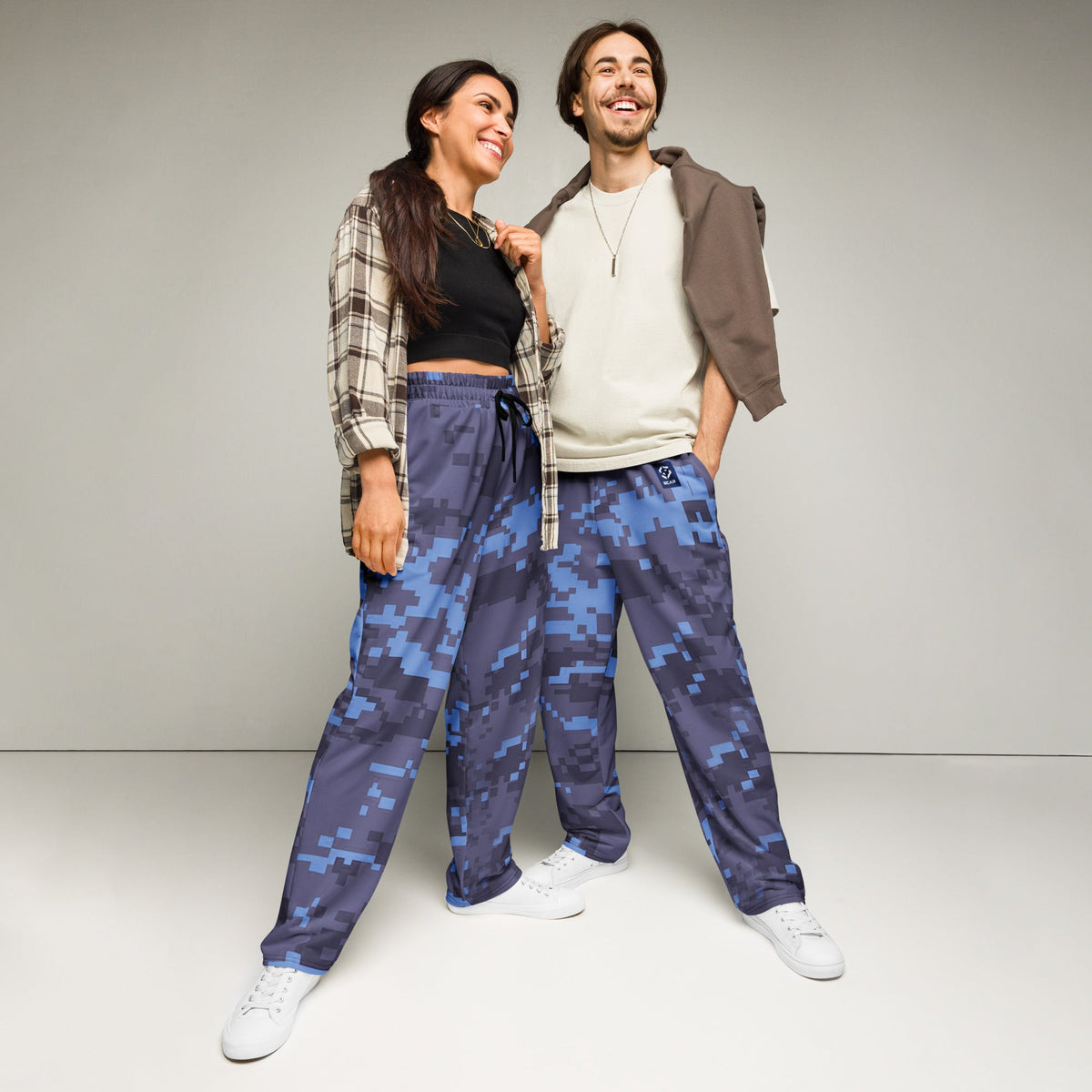 Digital camouflage wide-leg joggers on model, elastic waist and drawstring, relaxed fit
