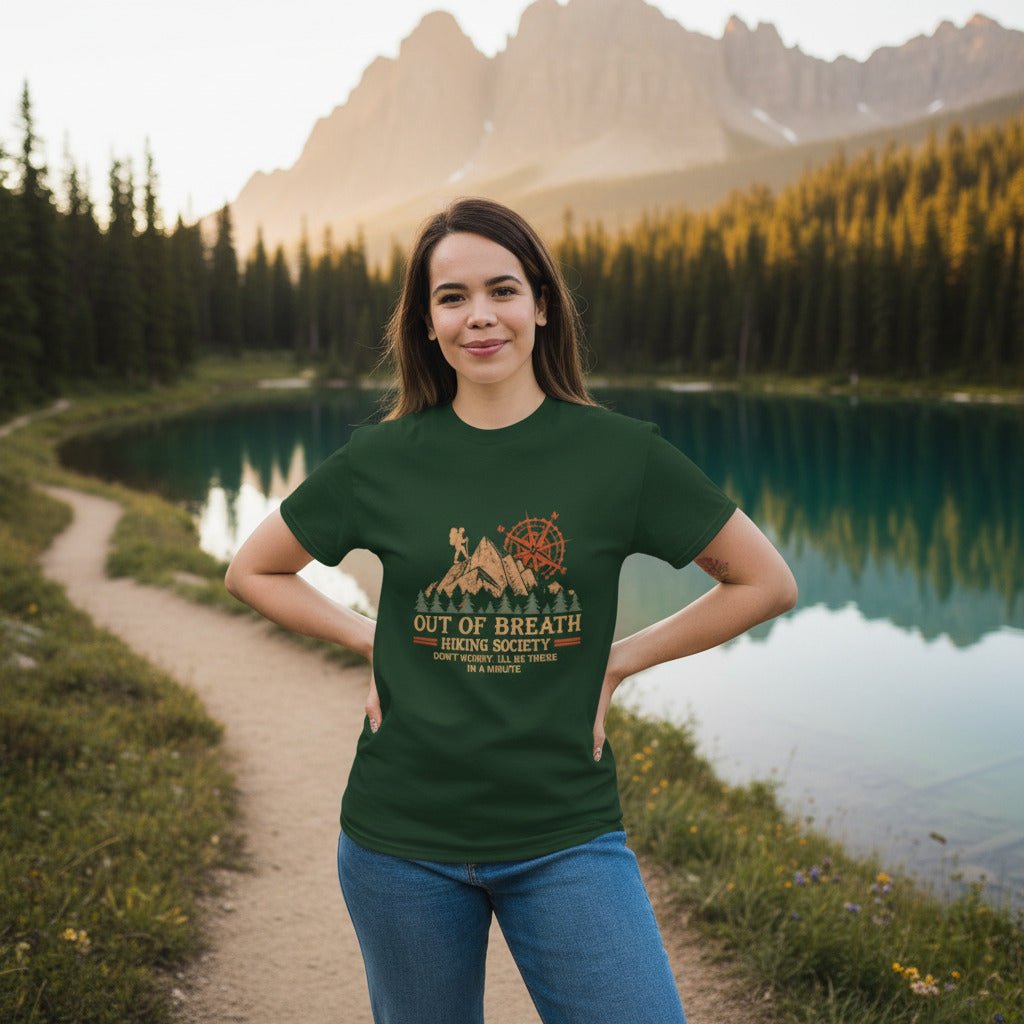 Forest green hiking graphic T-shirt with cabin and compass emblem, worn by a woman
