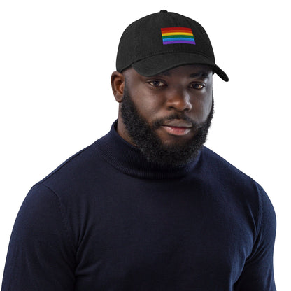 Black denim baseball cap with Pride rainbow flag embroidery on the front, worn
