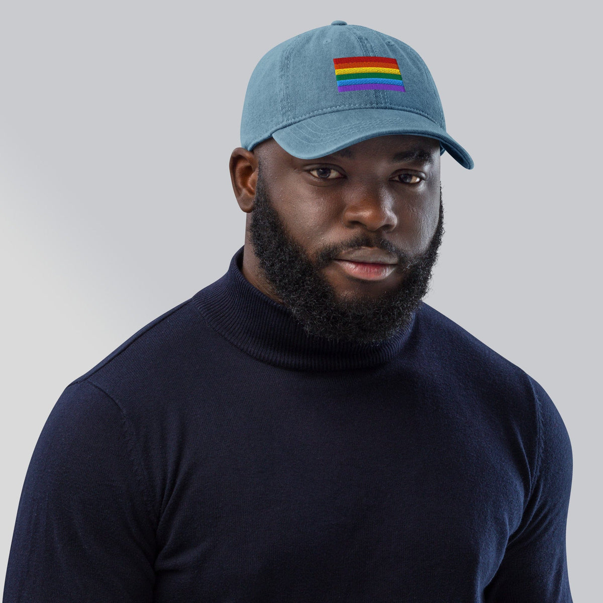 Light blue denim baseball cap with Pride rainbow flag embroidery, worn facing front