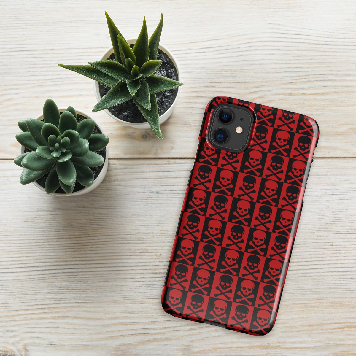 Red iPhone snap case featuring black skull pattern, smooth matte finish, camera cutouts