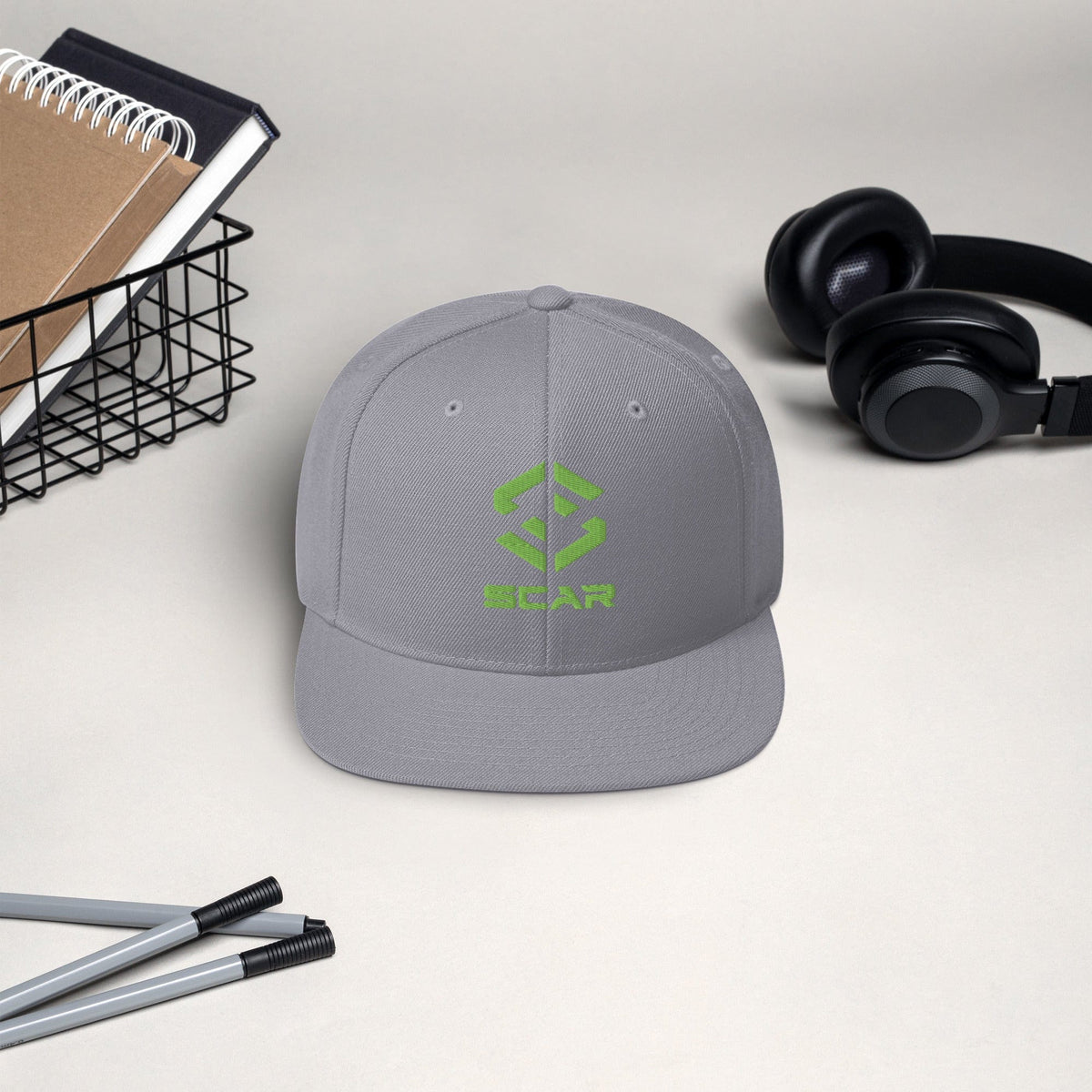 Gray snapback hat with green SCAR logo embroidery and structured front panels.