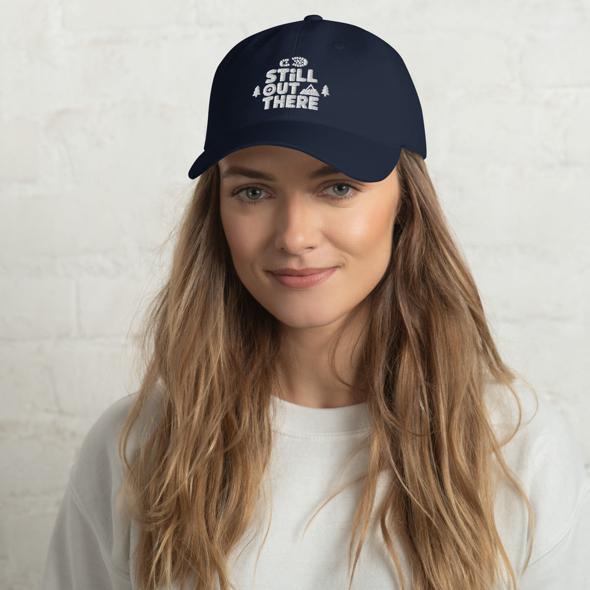 Navy dad hat with embroidered “STILL OUT THERE” logo on front and curved brim.