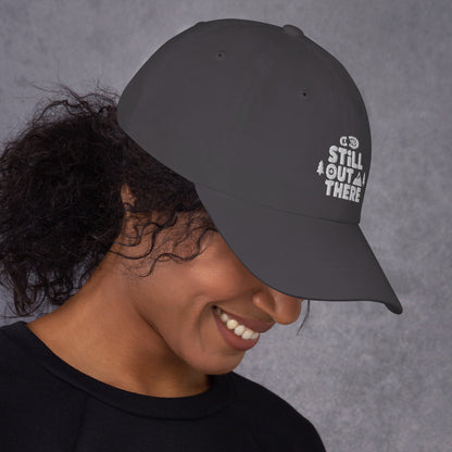 Gray baseball cap with embroidered “STILL OUT THERE” logo on front and curved brim.