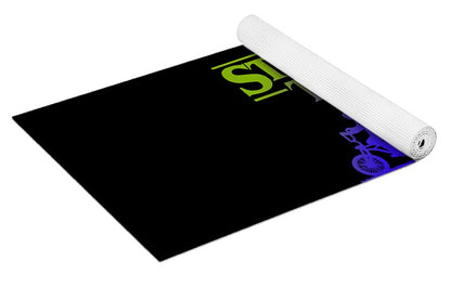 Kids yoga mat rolled with black surface and Stranger Things logo in green and purple