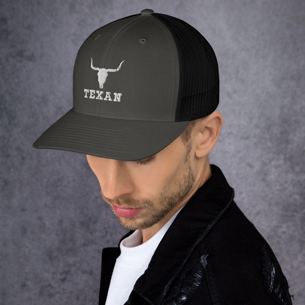 Olive/dark gray trucker hat with white bull head and “TEXAN” lettering on the front.
