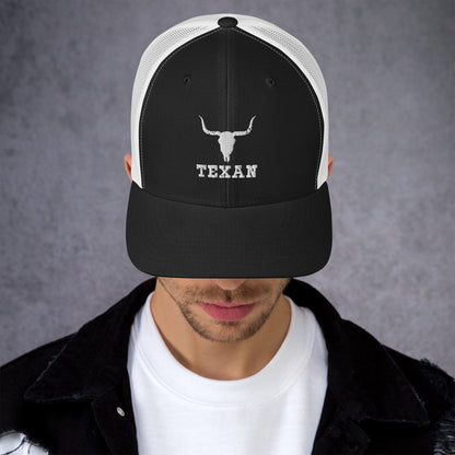 Black trucker hat with white mesh back, white bull head, and “TEXAN” front lettering.