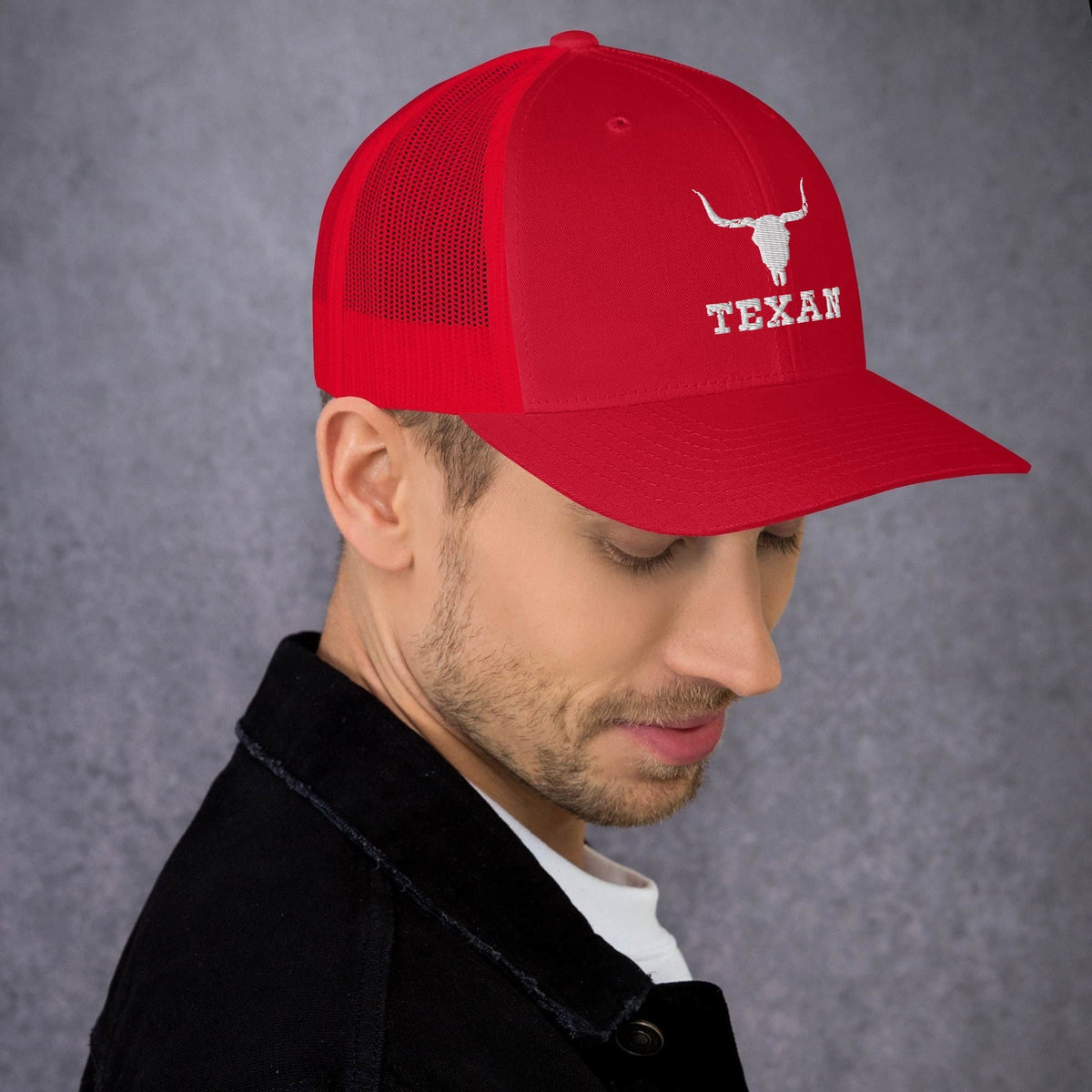 Red trucker hat with mesh back and white bull and “TEXAN” patch on front panel