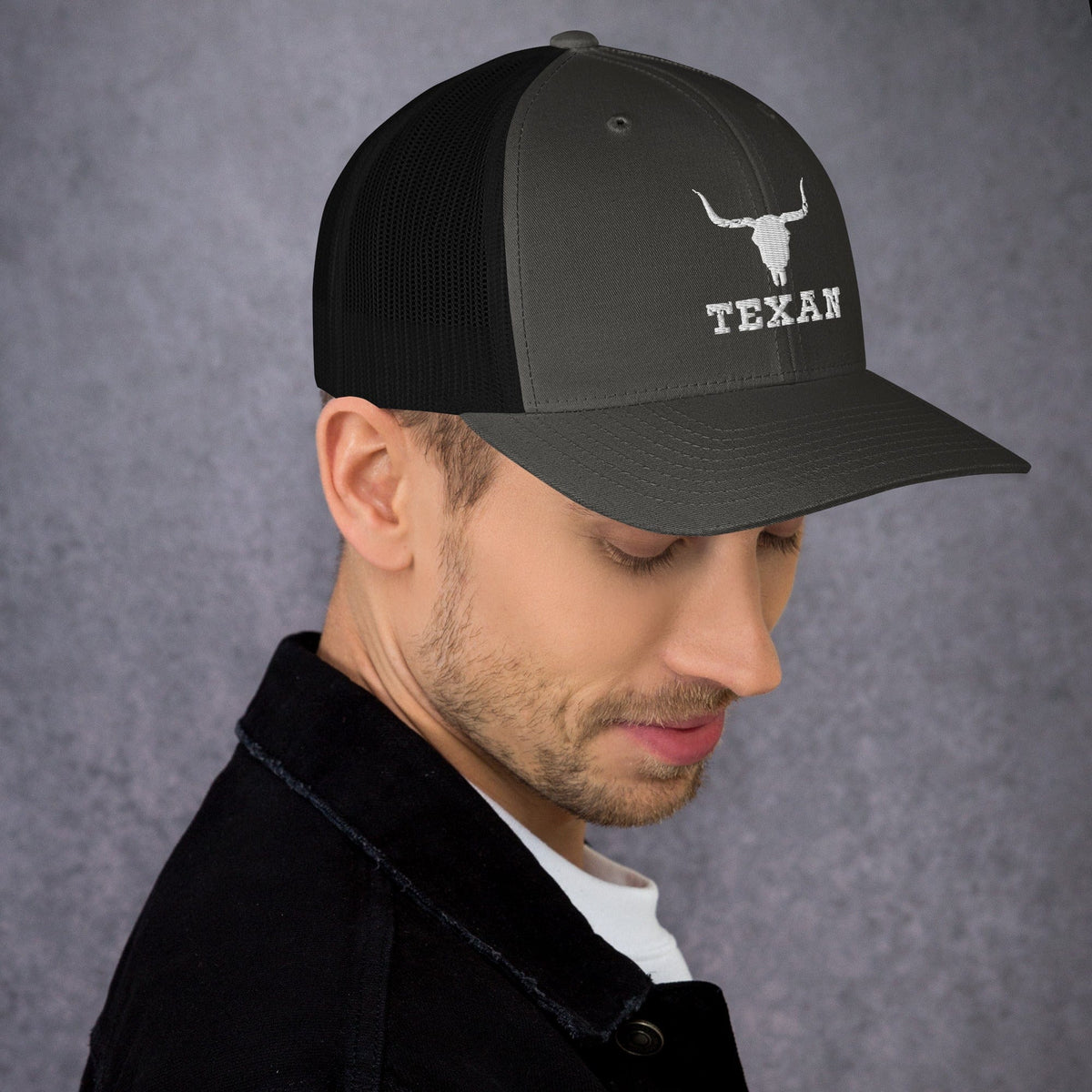 Black trucker hat with mesh back and white bull and “TEXAN” patch on front panel