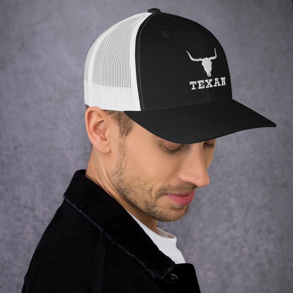 Black and white mesh trucker hat with a white bull head icon and “TEXAN” on front.