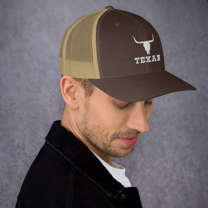 Olive and brown trucker hat with mesh back and white bull and “TEXAN” patch