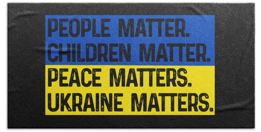 Black beach towel with bold blue and yellow text: People, Children, Peace, Ukraine Matters