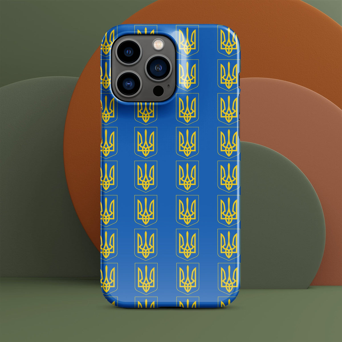 Blue iPhone case with repeating yellow Tryzub trident and shield motif; camera bump visible.