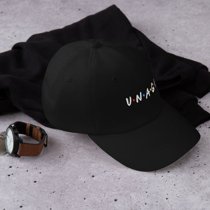 Black embroidered cap with V.N.A.G.I logo on front, lying on black fabric