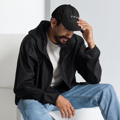 Black embroidered baseball cap worn by man, UNAGI logo on front